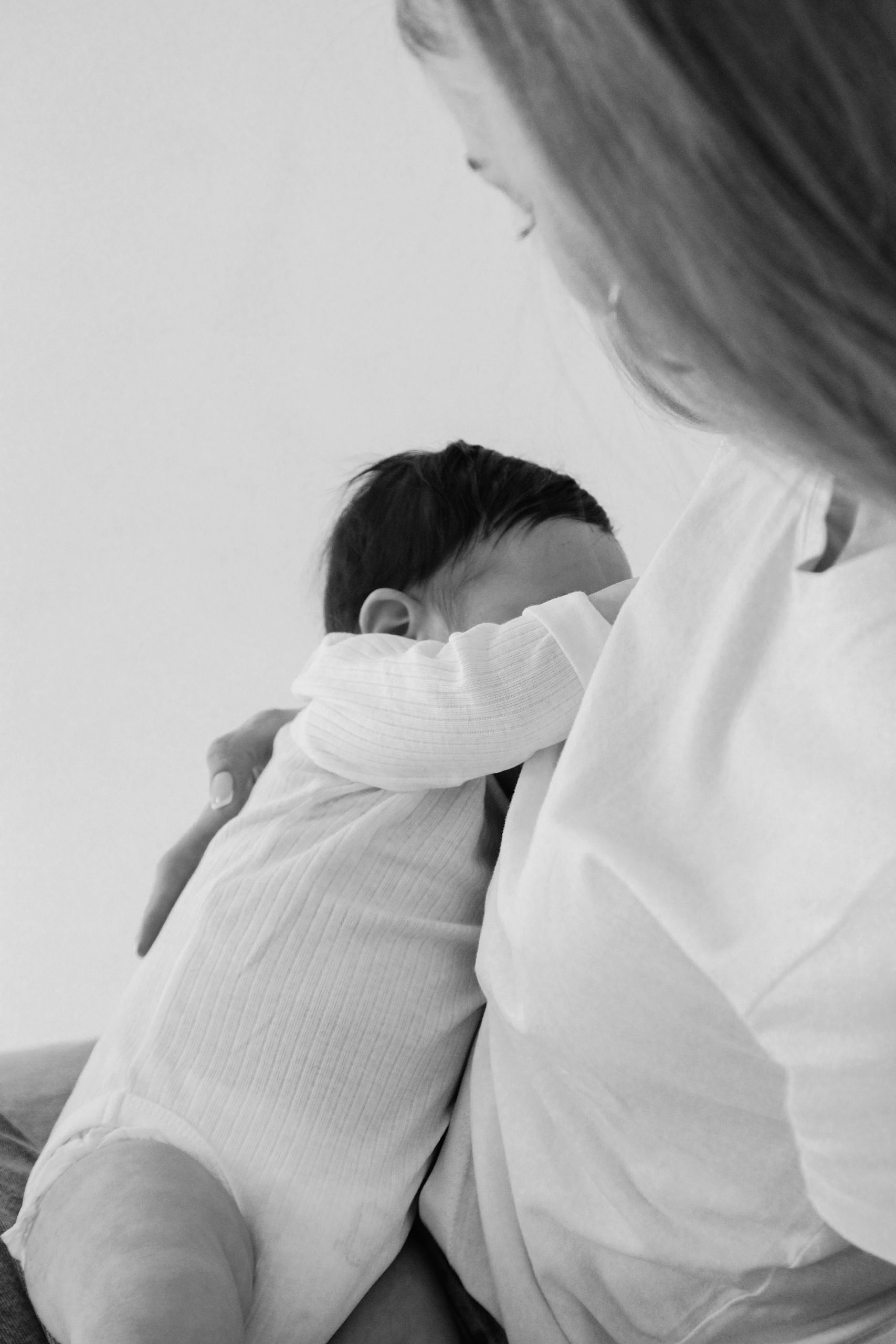 Mother holding a newborn in deep reflection near window light